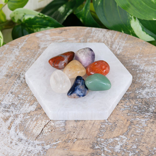 Seven chakra stones on a hexagon charging plate
